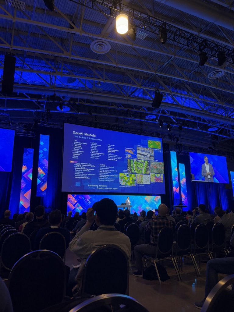 A photograph of a conference presentation on GeoAI Models.